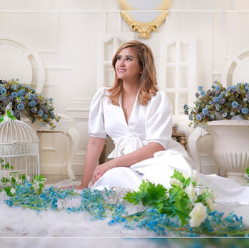 A beautiful woman in a white dress posing at the white room of Alleycat Studio