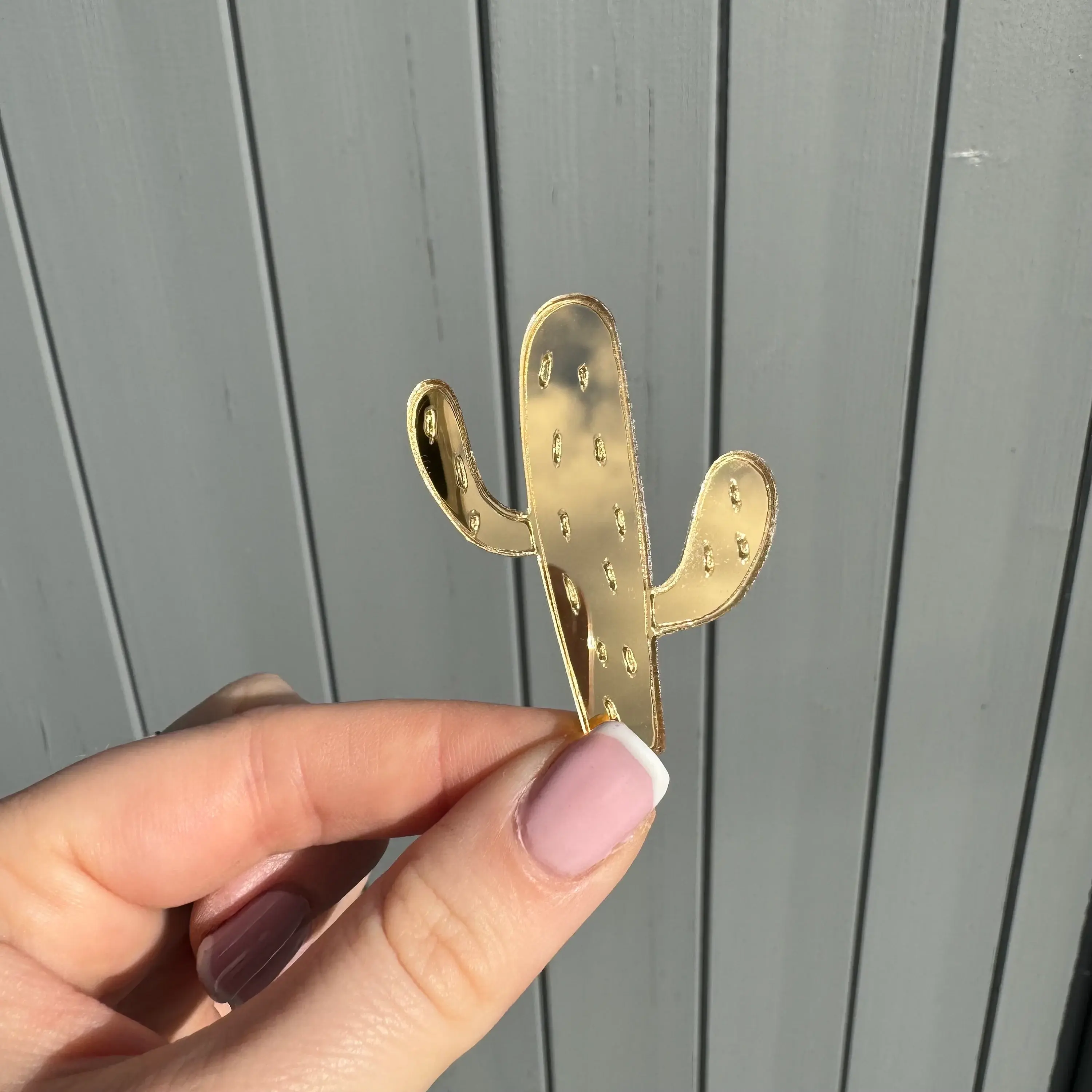 Hand holding a gold cactus decoration