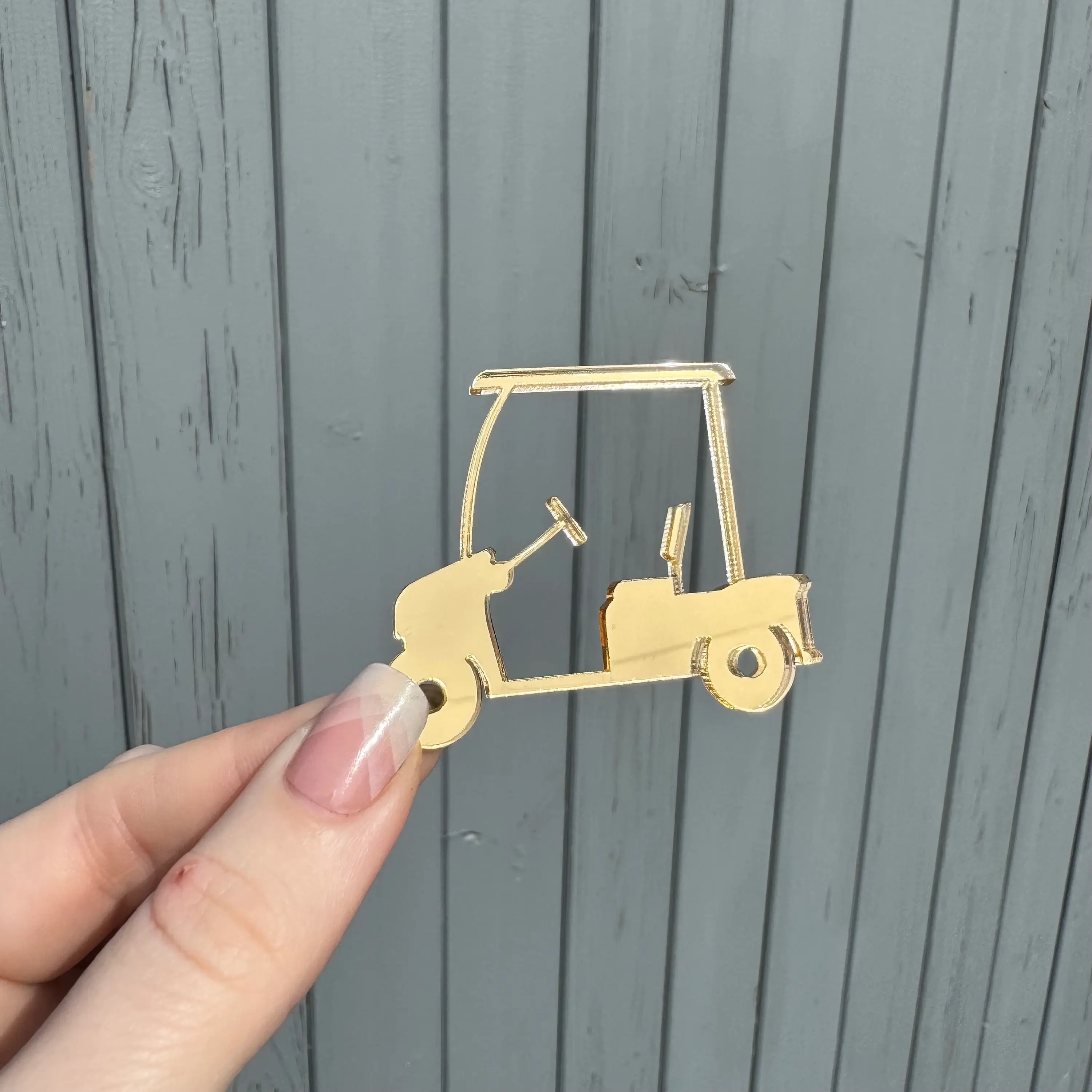 Hand holding small wooden golf cart cutout