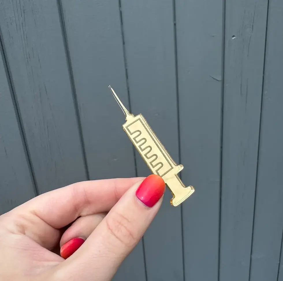Hand holding a small golden syringe