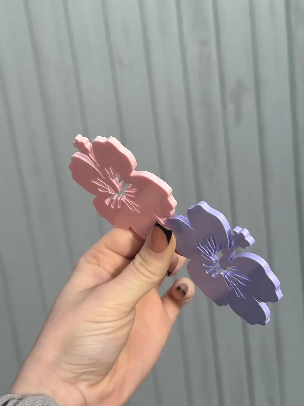 Thumbnail: Hand holding pink and purple flower hair clips
