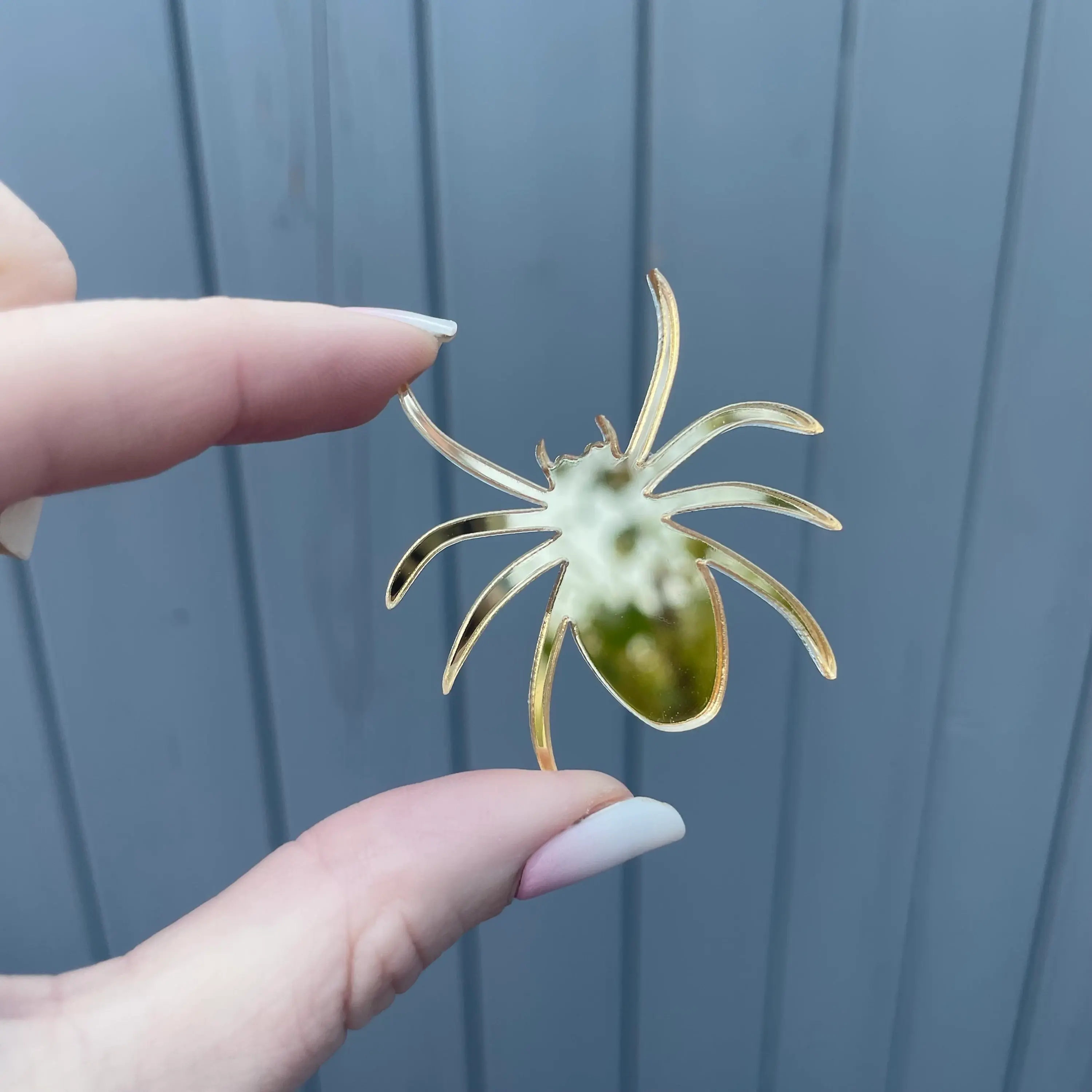 Fingers holding a yellowish-green spider decoration.