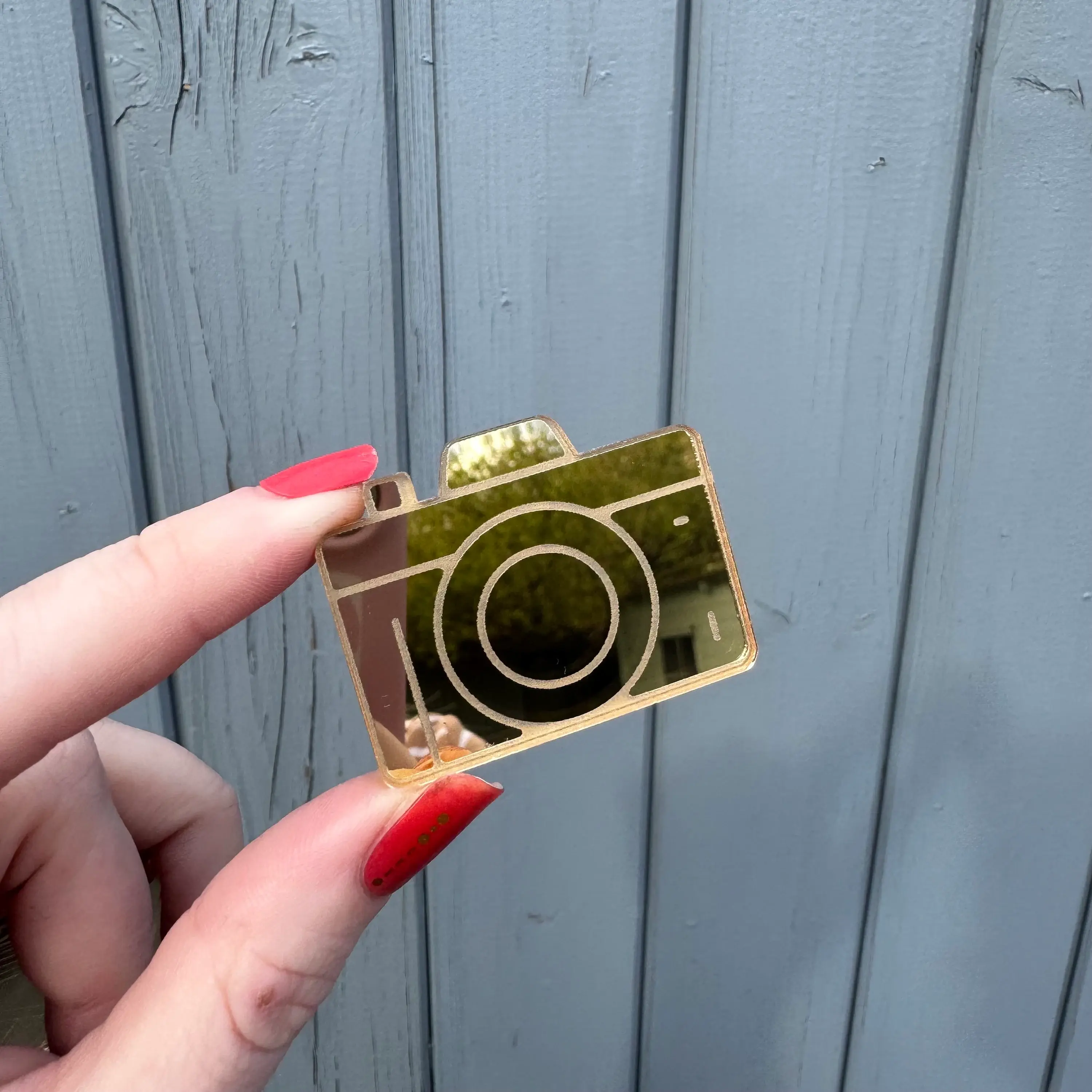 Hand holding a golden camera charm