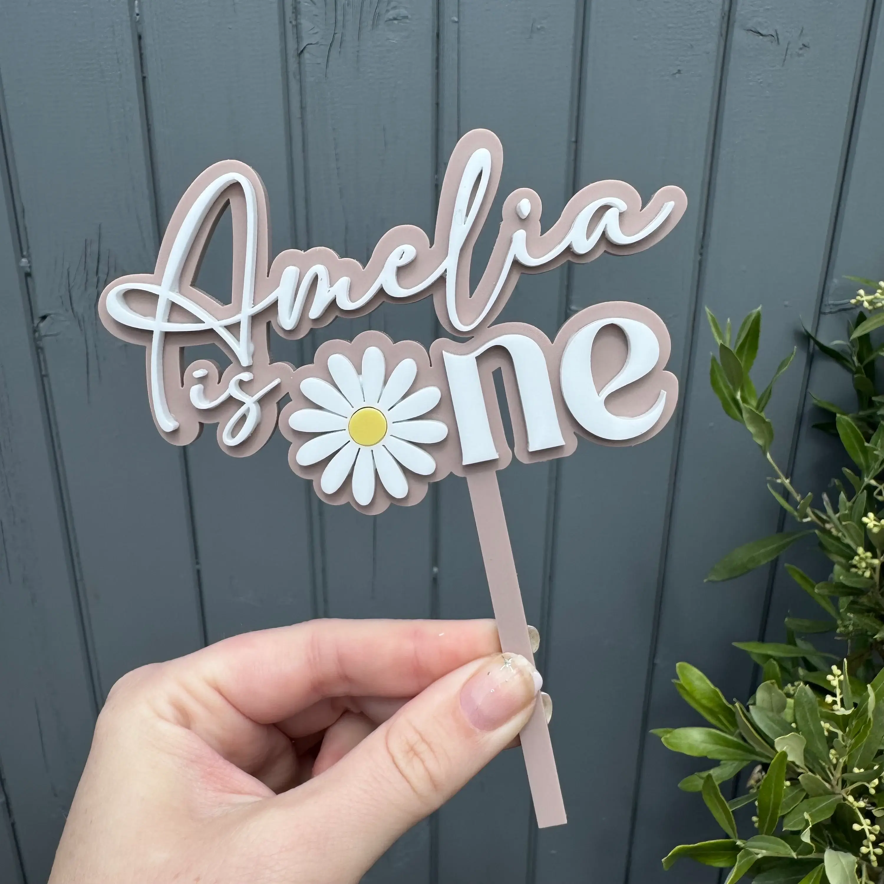 Cake topper 'Amelia is one' with a daisy