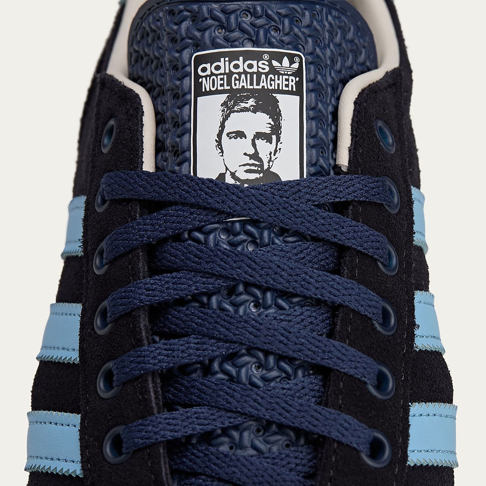 Siyah ve mavi renkte Adidas spor ayakkabının üst kısmı, mavi bağcıklar. Üst dilinde "adidas NOEL GALLAGHER" metni ve bir yüz resmi var.