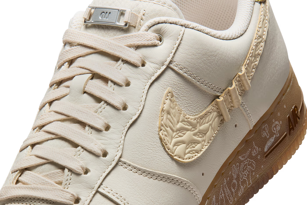 Krem tonlarında, bej dantel detaylı bir spor ayakkabı detayı; yan kısımda kabartmalı desenli bir logo ve tabanda AIR yazısı görülüyor.