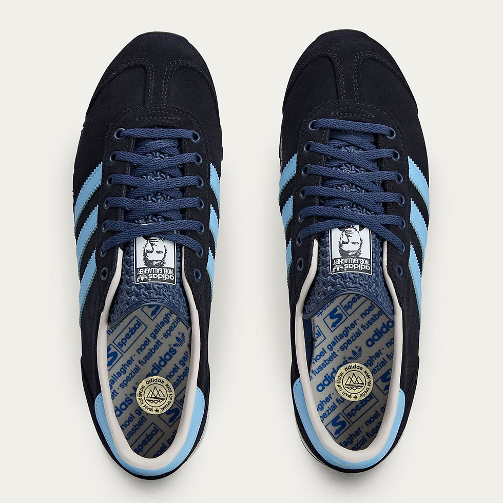 Siyah spor ayakkabılar üstten görünüm. Mavi şeritler, bağcıklar. İç tabanda adidas, Noel Gallagher metni. Temiz, minimal arka plan.