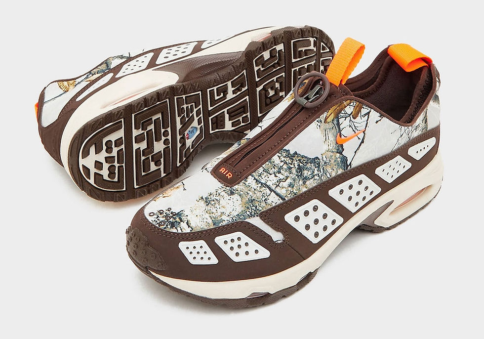 Kahverengi ve beyaz desenli spor ayakkabı, üzerindeki turuncu detaylar ve "AIR" metniyle dikkat çekiyor. Arka planda açık gri zemin.