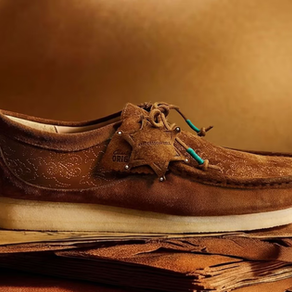 Kahverengi süet ayakkabı, krem tabanlı, doku detaylı. Arka planda yumuşak kahverengi tonlar. Üzerinde "ORIGINALS" ve "ANDERSSON BELL" yazısı.