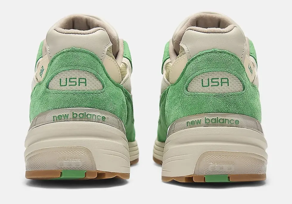 Yeşil ve krem renklerde New Balance spor ayakkabıların arkadan görünümü. USA ve New Balance yazıları dikkat çekiyor. Arka plan beyaz.