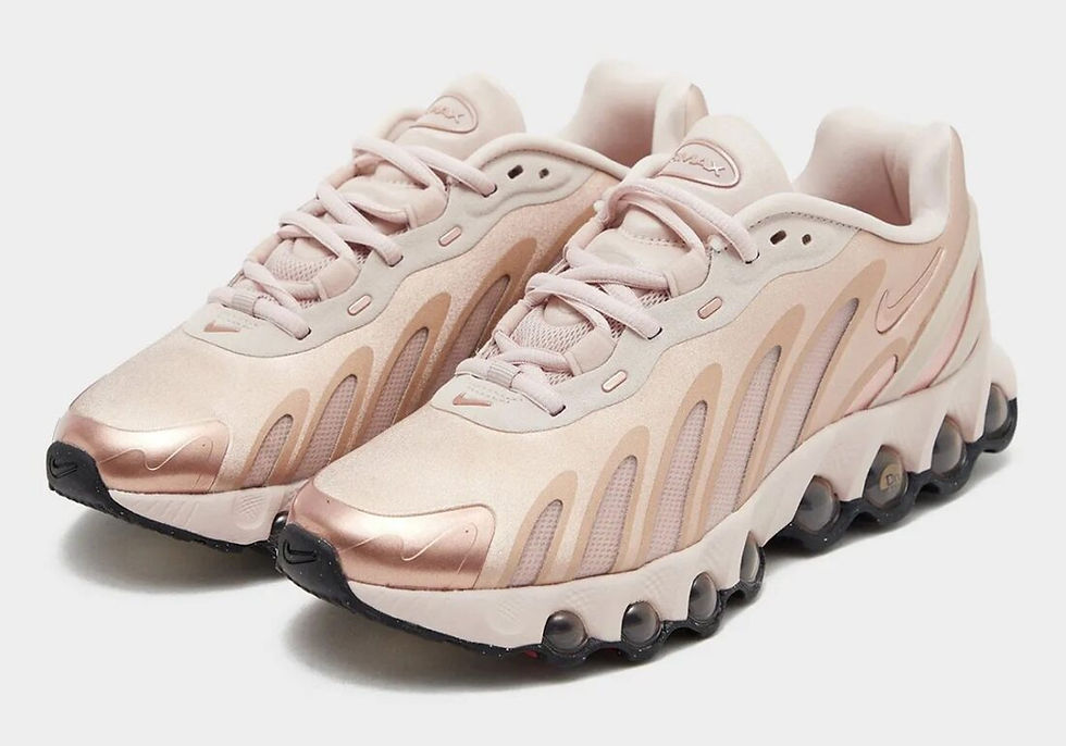 Pembe ve altın tonlarında Nike spor ayakkabılar, beyaz arka planda duruyor. Yumuşak, şık tasarım ve dalgalı desenler dikkat çekiyor.