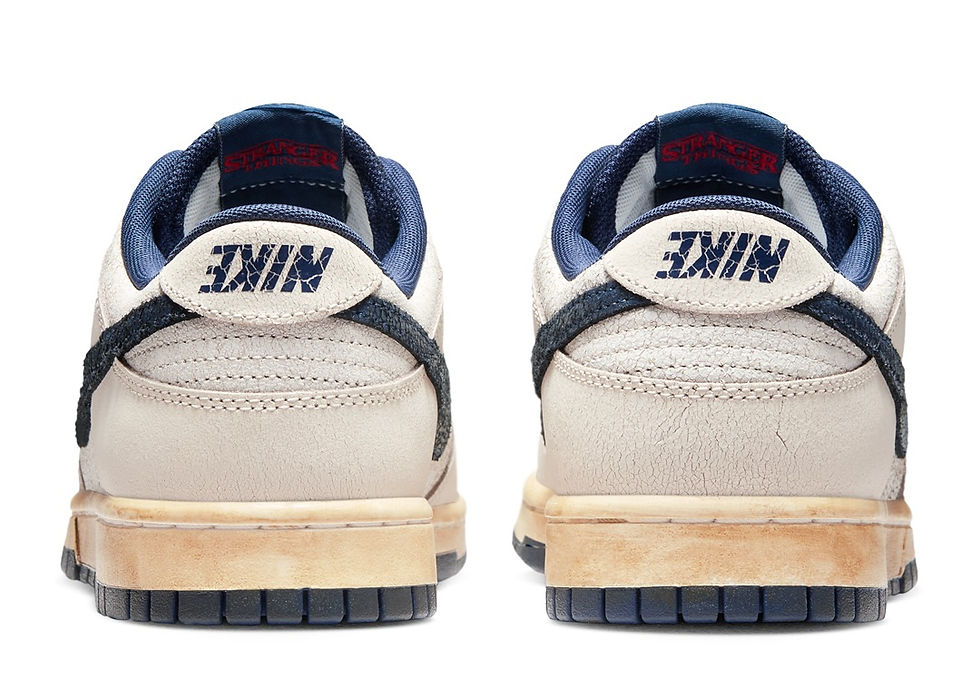 Bej ve lacivert Nike spor ayakkabılar, topuk kısmında "Nike" ve iç astarında kırmızı "Stranger Things" yazısı bulunuyor.