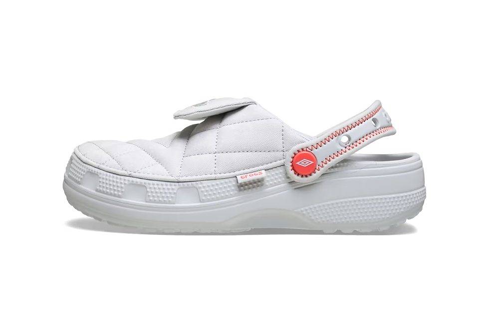 Beyaz, kapitone desenli, kırmızı detaylı bir terlik. Yanında "Crocs" logosu bulunuyor. Arka plan beyaz ve sade.