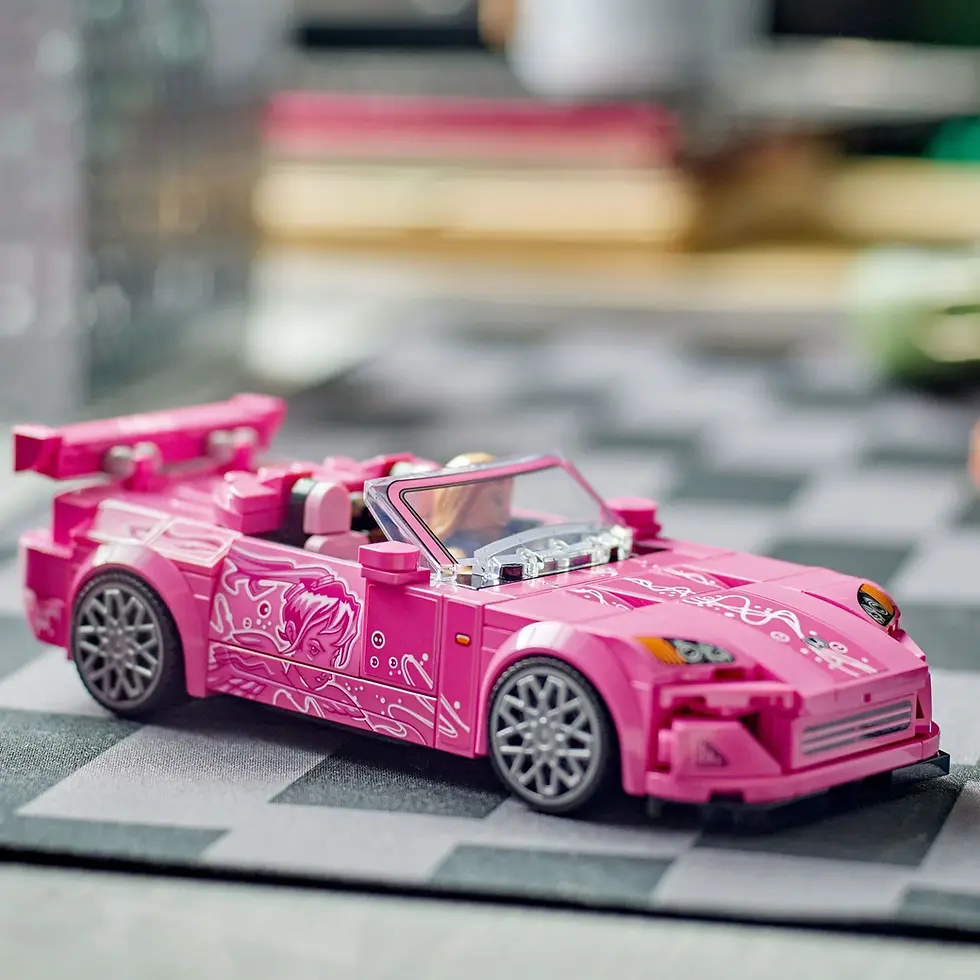 Pembe, desenli LEGO spor araba, içindeki figürle siyah-beyaz kareli zemin üzerinde duruyor, arka planda bulanık nesneler.