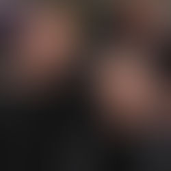 İki kişi birbirine sarılmış, gülümsüyor. Arka planda kalabalık ve sinema posteri var. Siyah ceket giyiyorlar, neşeli bir atmosfer.