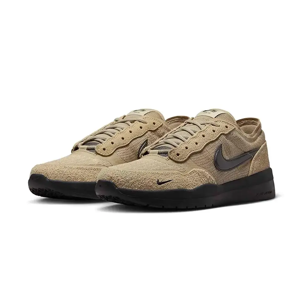 Koyu bej spor ayakkabılar, siyah tabanlı, yan kısımda siyah Nike logosu, beyaz zemin üzerinde hafif eğik yerleştirilmiş.