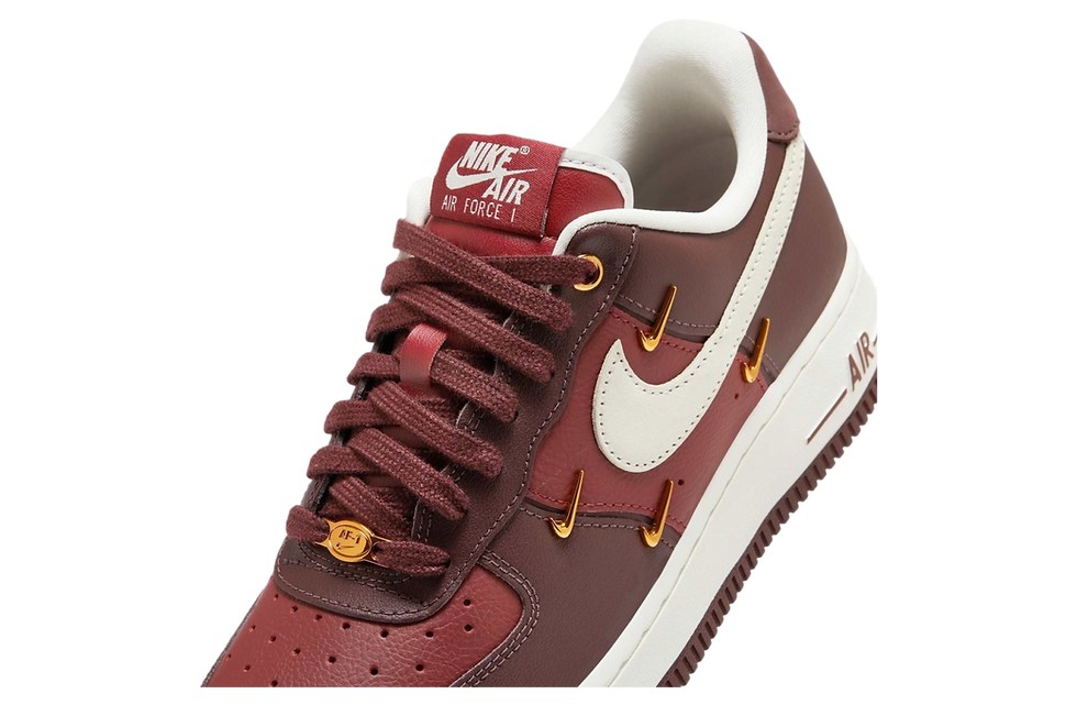 Kahverengi Nike Air Force 1 ayakkabı, beyaz logo ve kırmızı dil. Havalı ve sportif bir görünüm sergiliyor. Üzerinde "Nike Air Force 1" yazısı var.