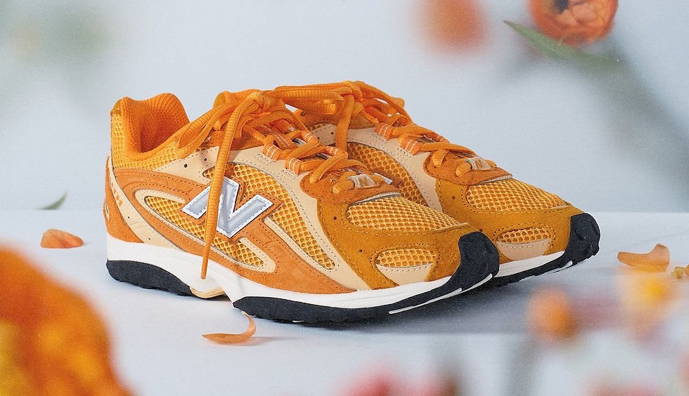 Turuncu ayakkabılar, beyaz bir zeminde duruyor. Ayakkabıların üzerinde "N" harfi var. Çevresinde turuncu çiçek yaprakları serpilmiş.