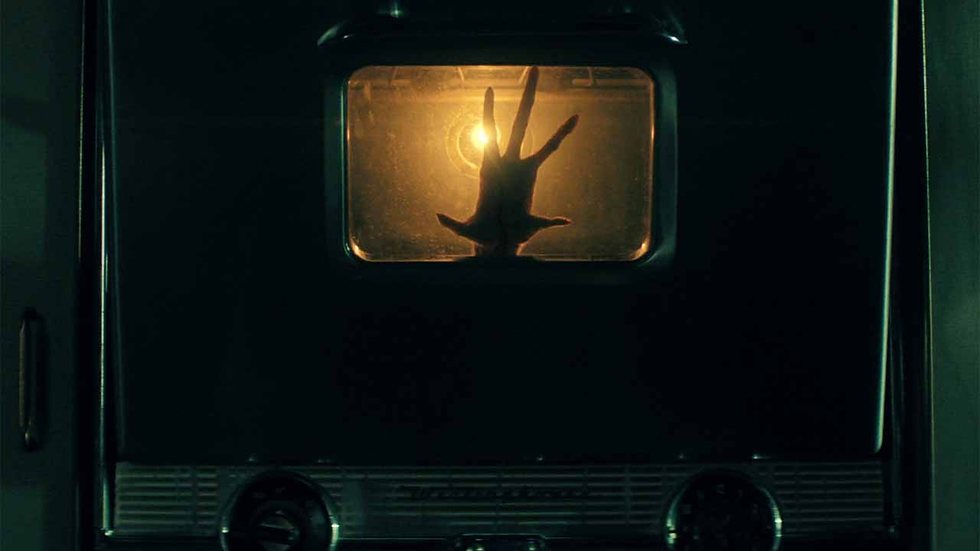 Karanlık bir ortamda eski tarz bir fırının içinde aydınlatılan bir el silueti, gizemli ve ürpertici bir atmosfer yaratıyor.