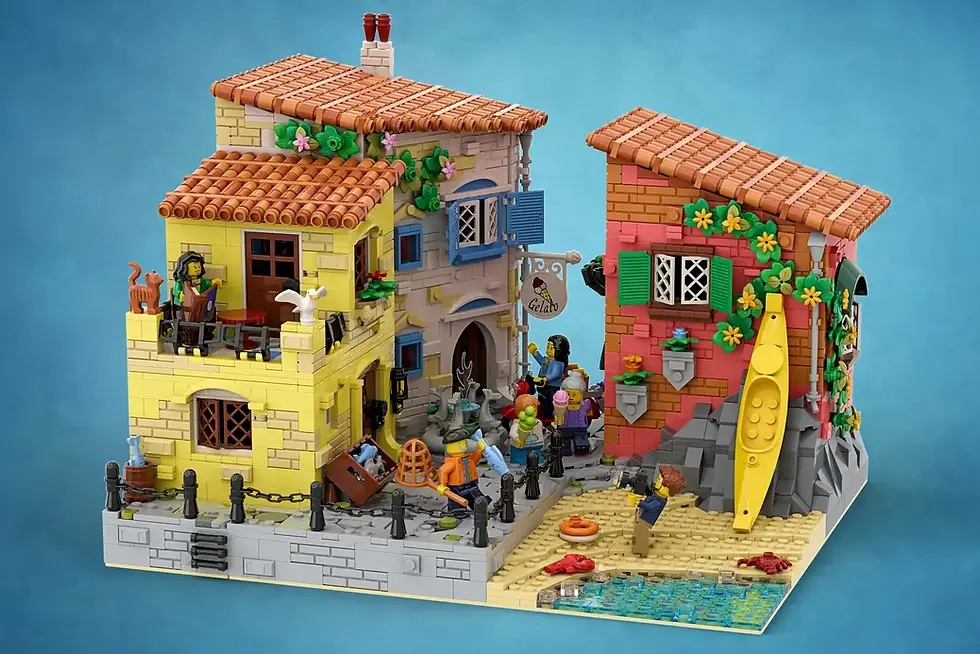 İki renkli LEGO bina, sahil, insan figürleri, sarı kayak ve "Gelato" tabelası. Arka planda mavi deniz ve sevimli ayrıntılar.