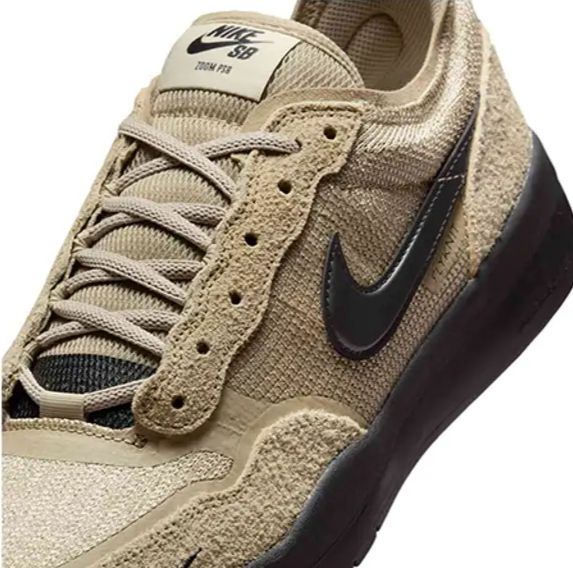 Bej rengi Nike ayakkabı yakın çekim. Siyah logo, bağcıklar, dokulu saya. Üstte "Nike SB Team Fun" yazısı. Spor, şık tasarım.
