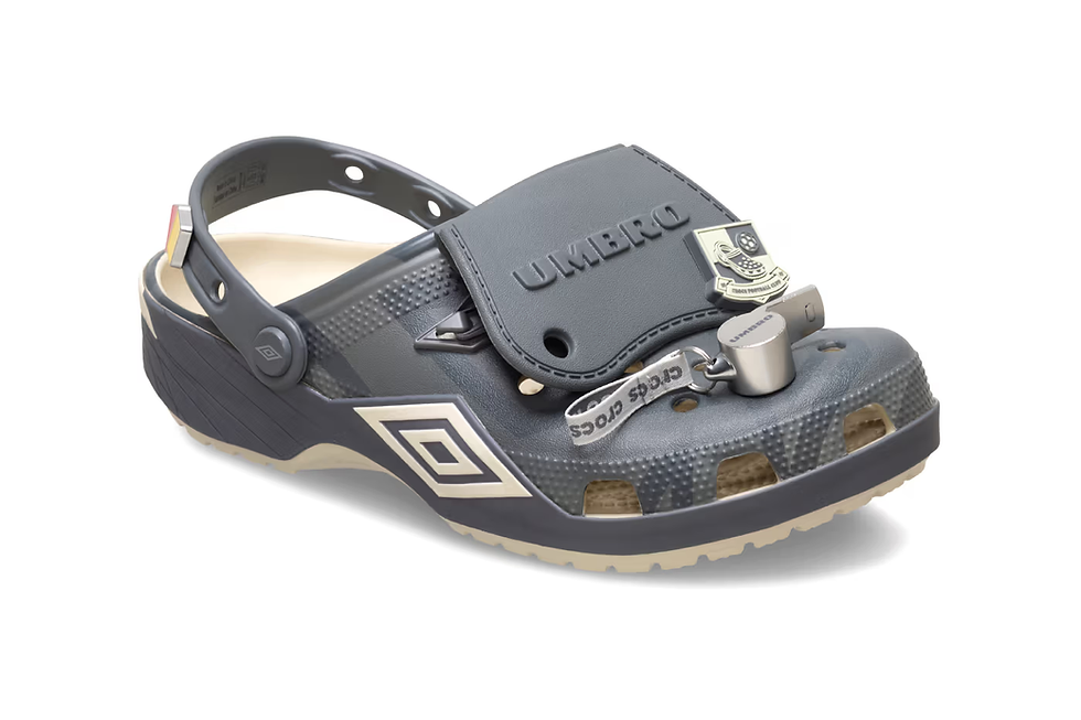 Koyu gri, topuk kayışlı bir Crocs terlik. Üzerinde Umbro logosu, metal bir kilit aksesuarı ve "Crocs" yazılı bir şerit bulunuyor.