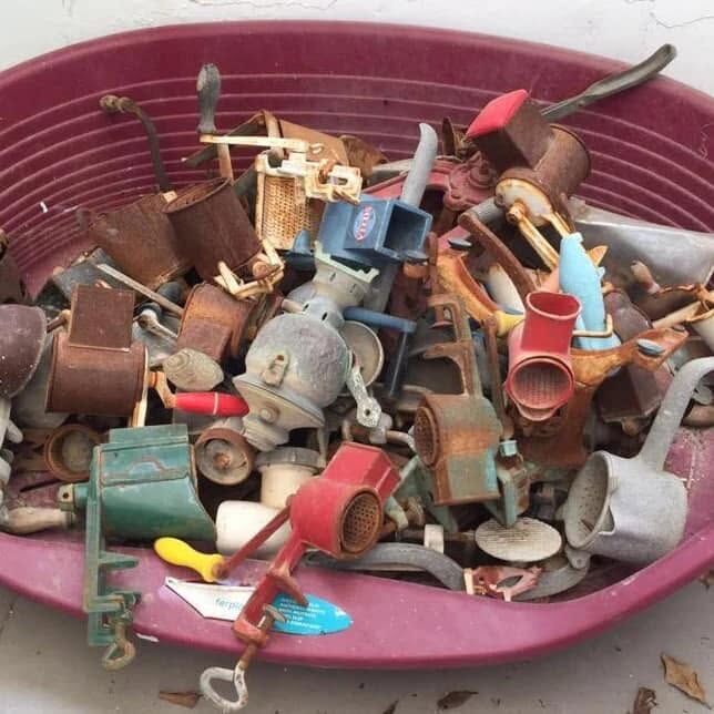 A pink bowl full of old grinding machines and cheese graters