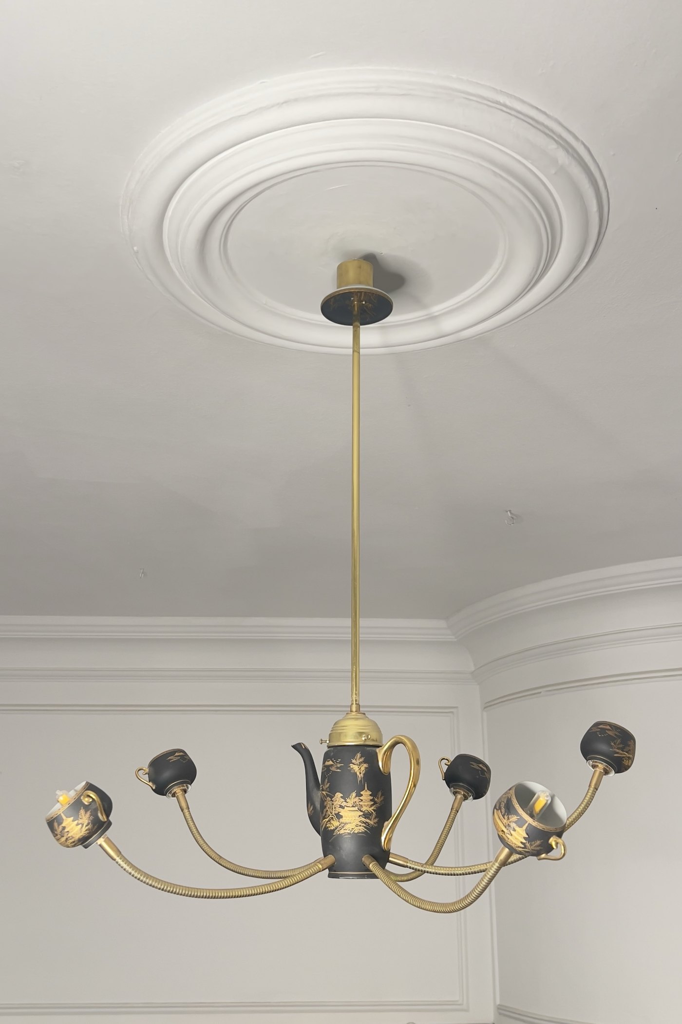 The Empress chandelier switched on, under a plaster ceiling rose