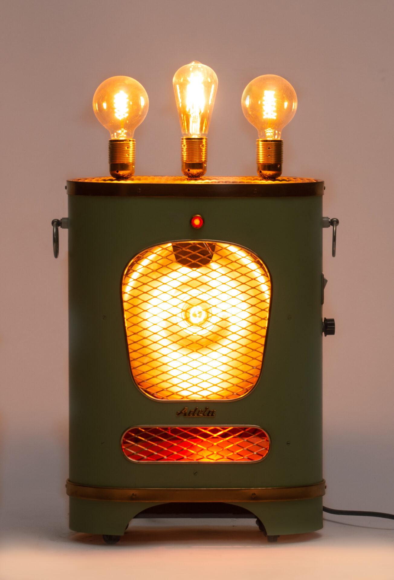 The Green Heater, switched on: the three bulbs and the grille glowing amber