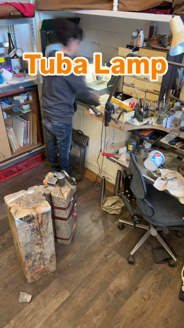 The studio, wide: a workbench, shelves of tools and a block of wood on the floor