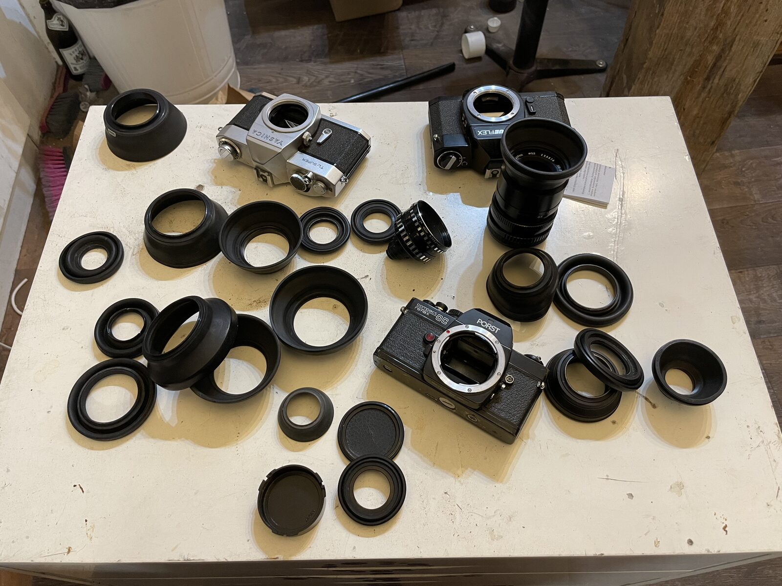 Camera Lamp before: Camera bodies, lenses and hoods laid out on a white table