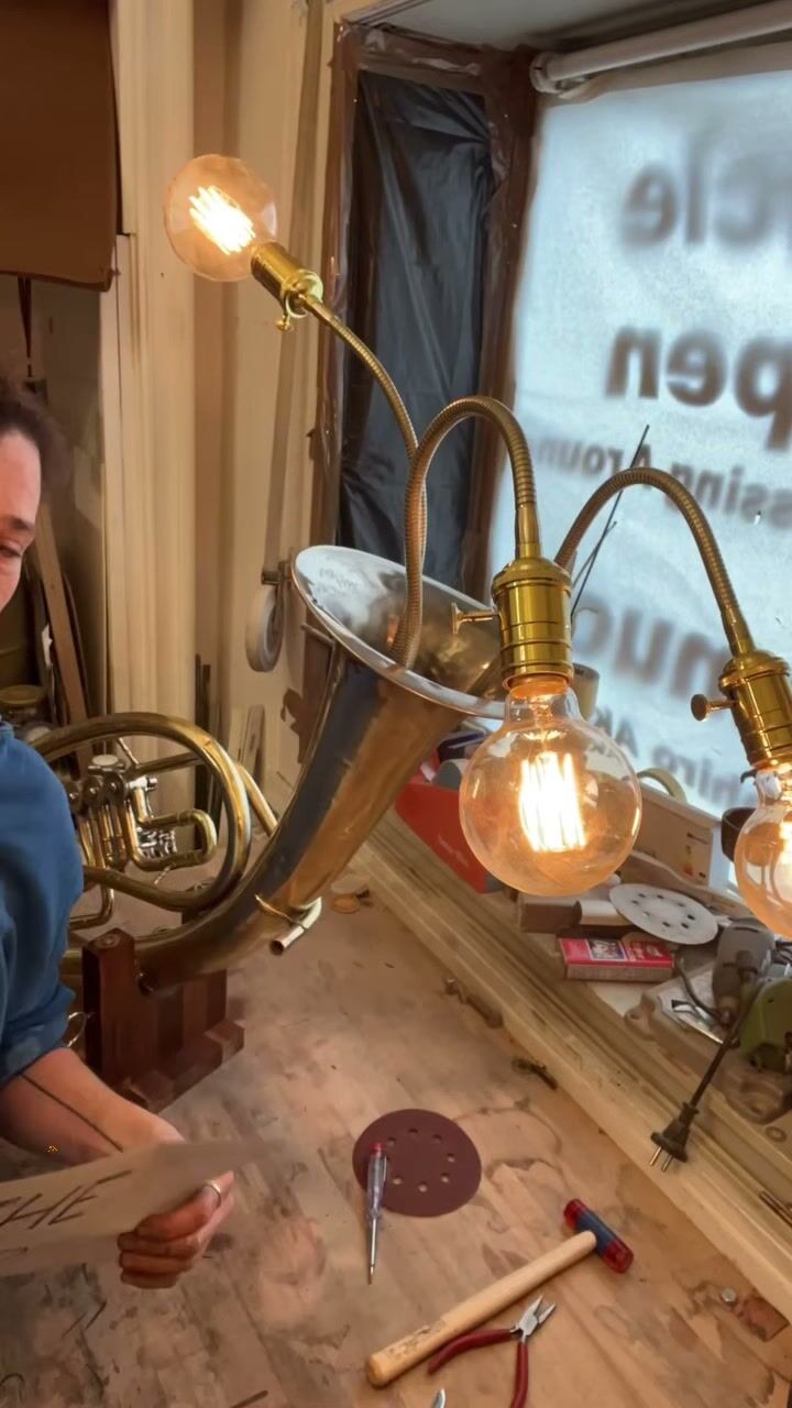 The Tuba lamp switched on at the studio bench, Keren beside it
