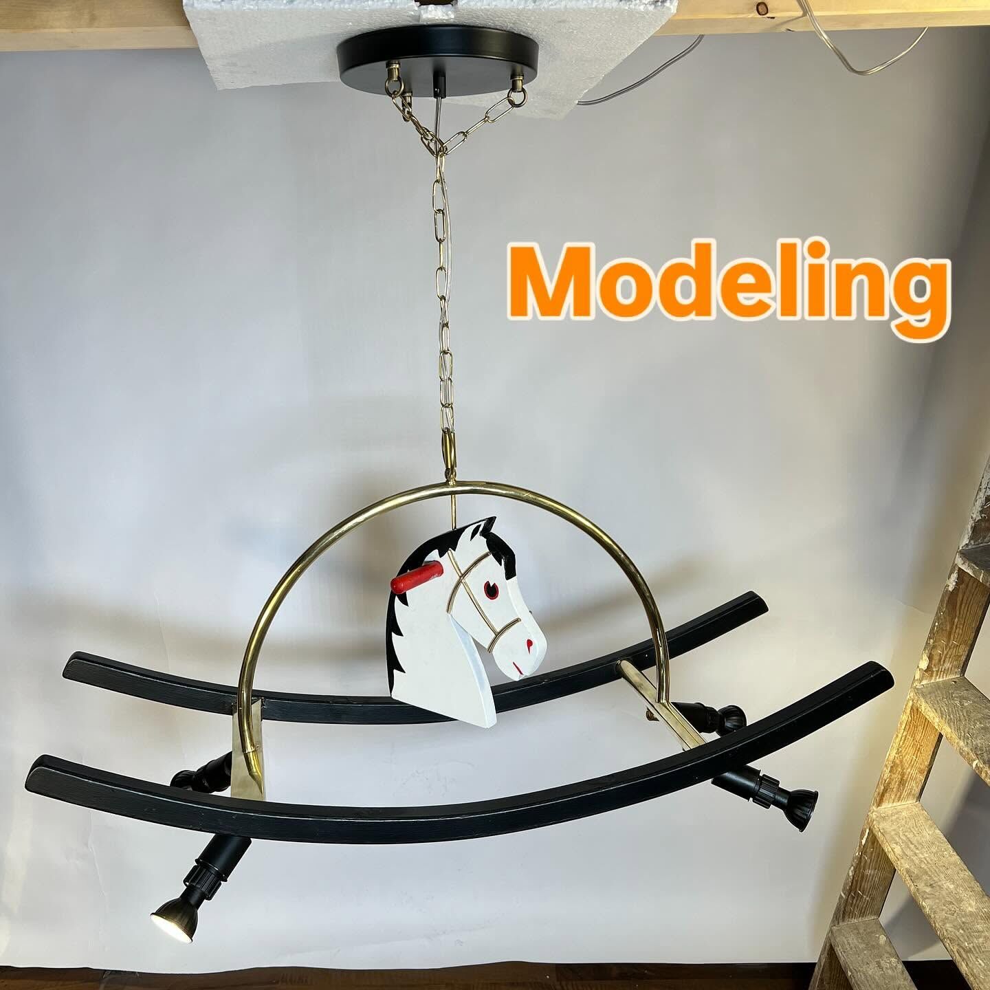 Story frame: the chandelier test-hung, captioned Modeling