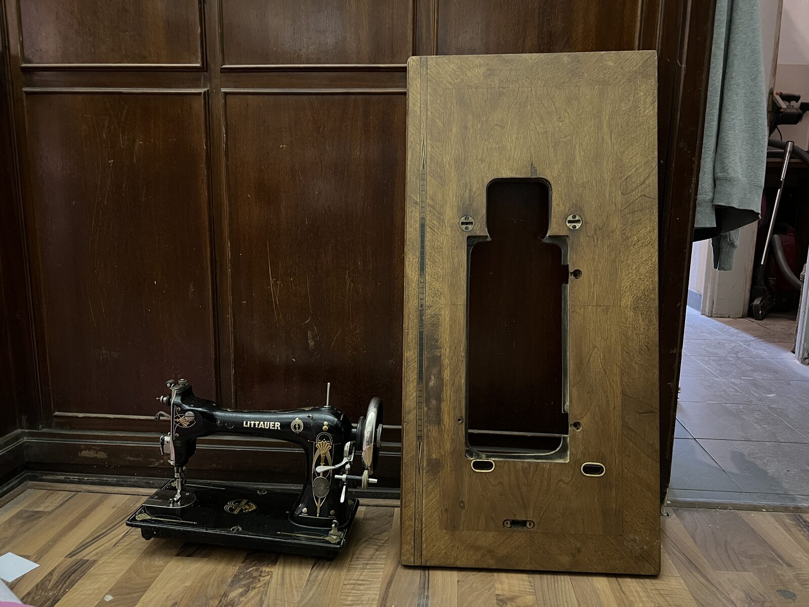 Machine head next to the table top with the cut-out, against a wooden door