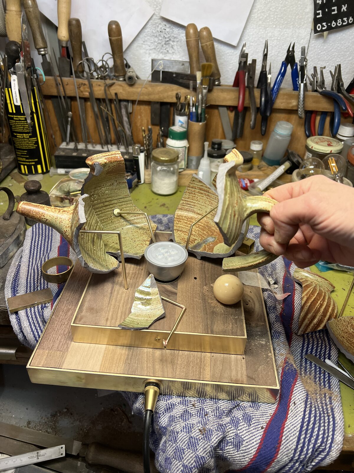 Teapot shards and brass parts arranged on the base