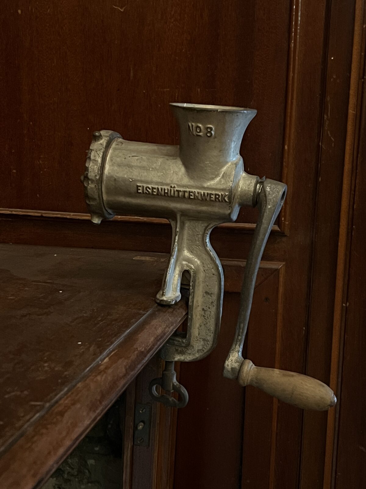 Meat Grinder before: Eisenhuettenwerk meat grinder clamped to a wooden sideboard, radiator behind