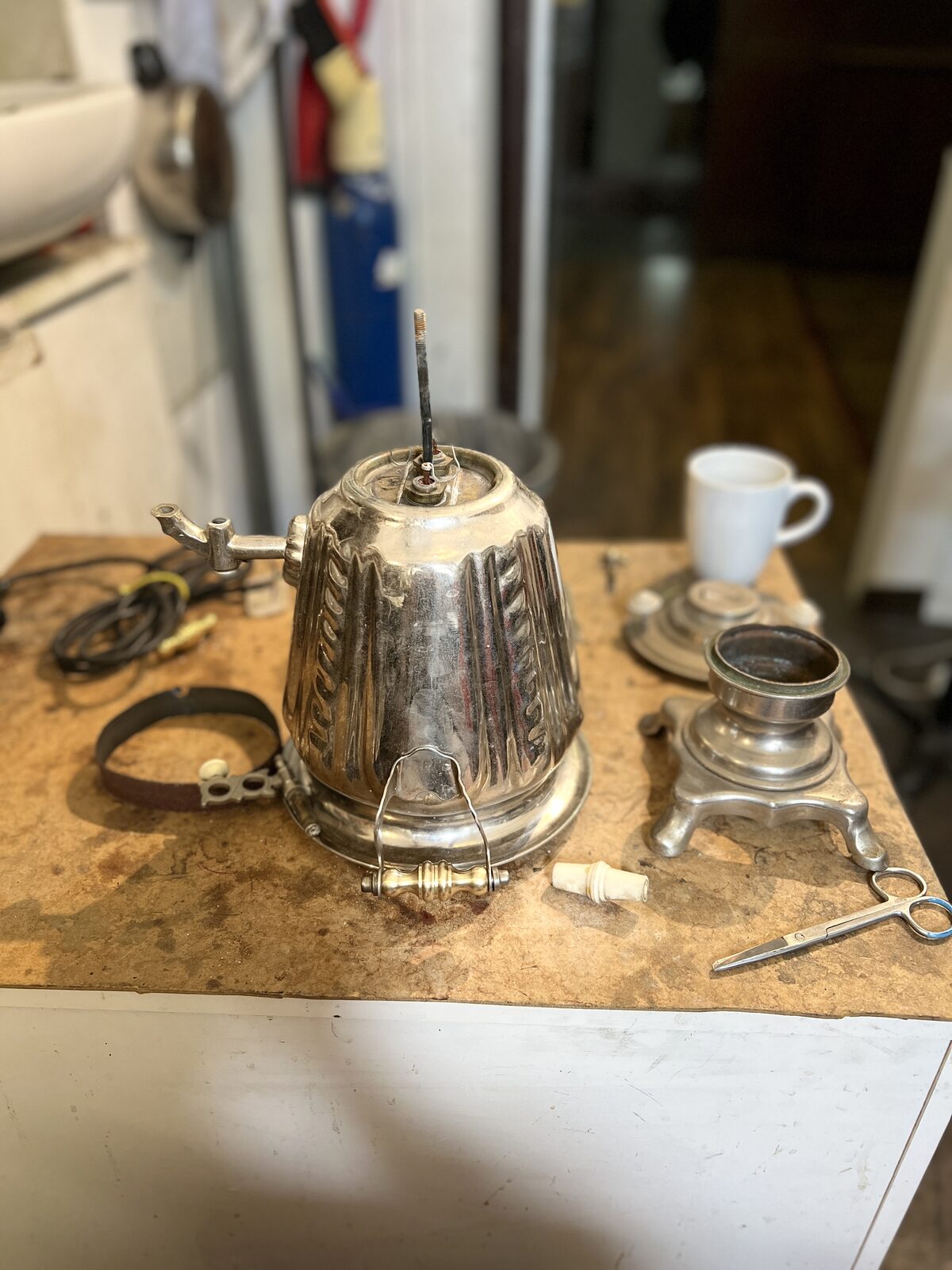 Samovar body and its base and tap in parts on the bench
