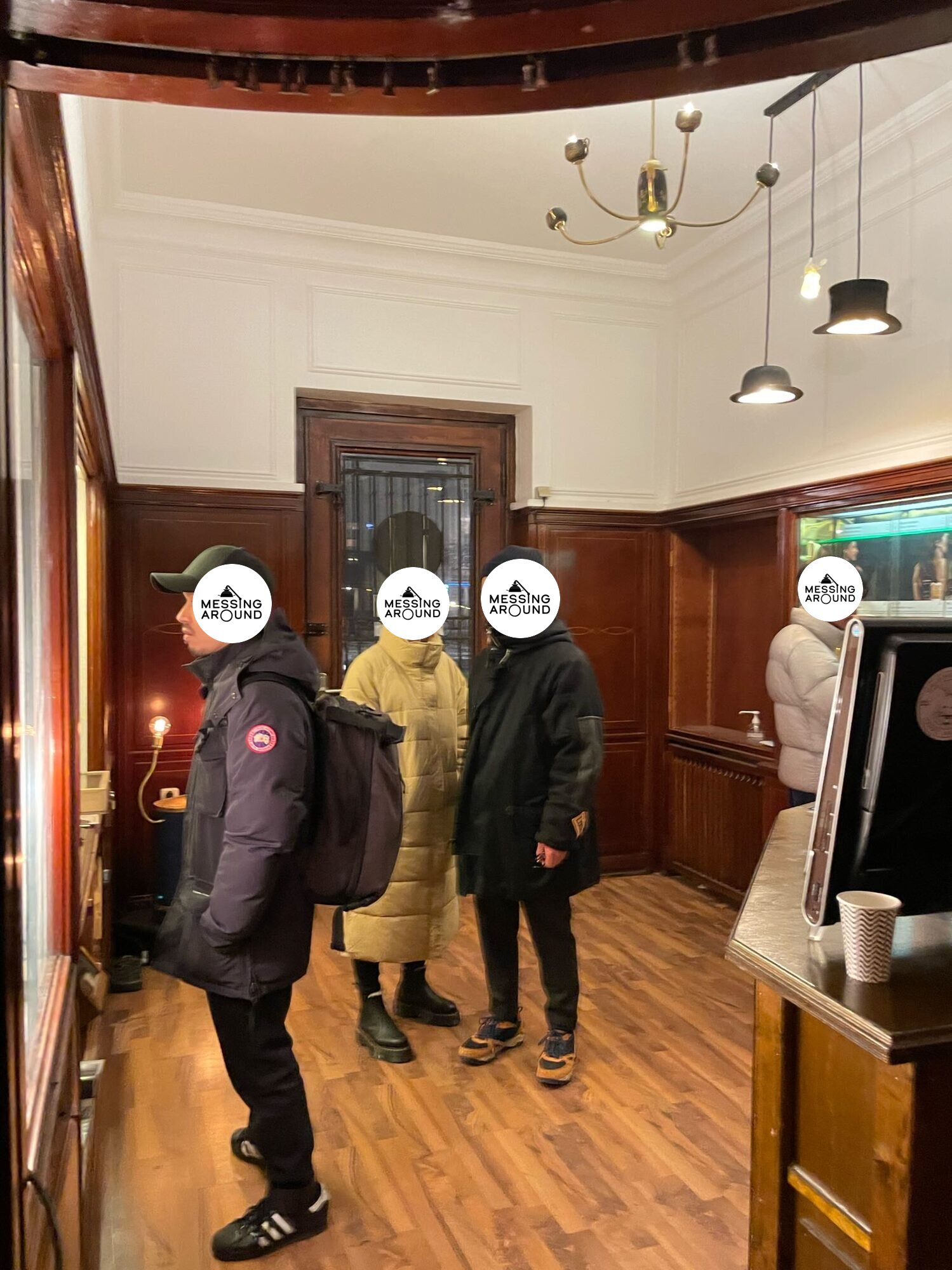Visitors in a wood-panelled room, the Empress lit above them beside two hat pendants