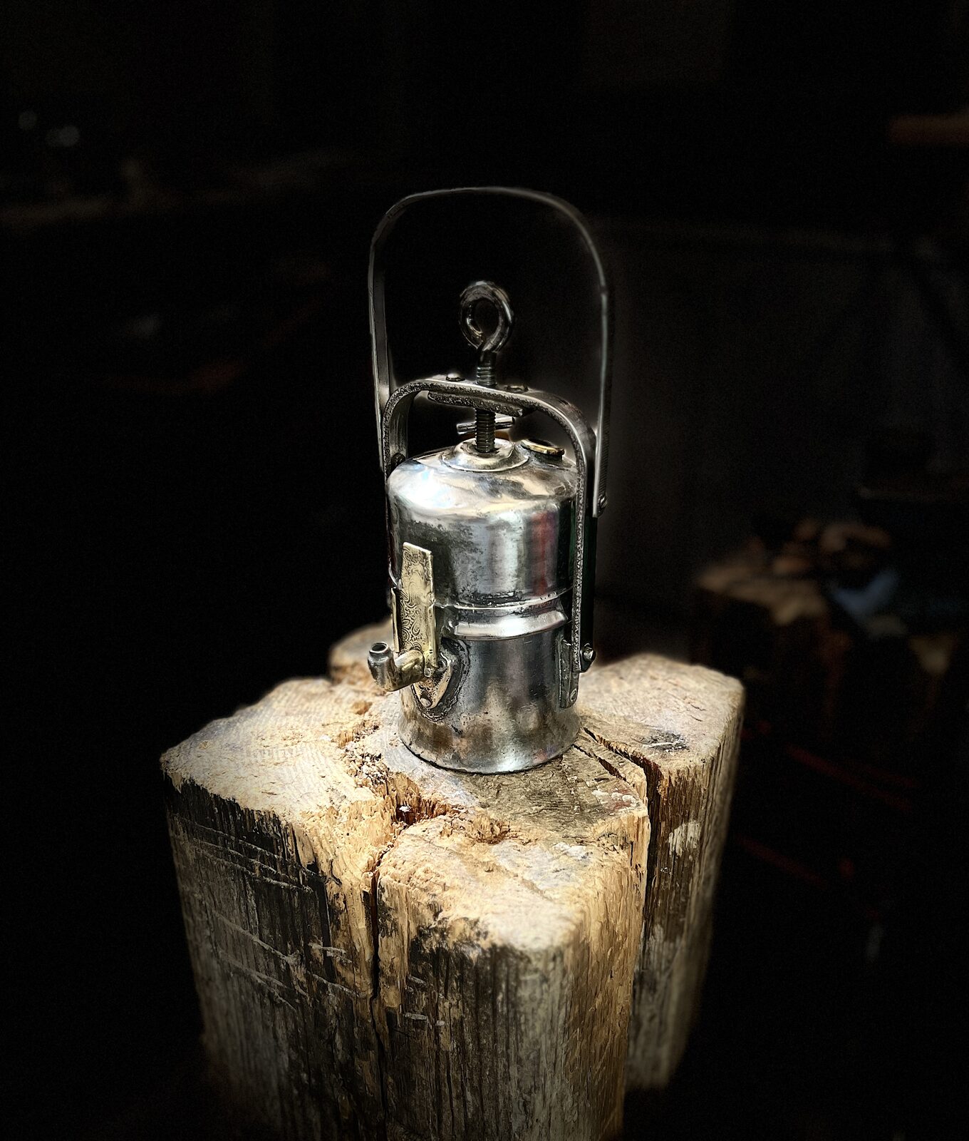 Brenner Wall Lamp before: Carbide lamp with handle on a stump, dark workshop