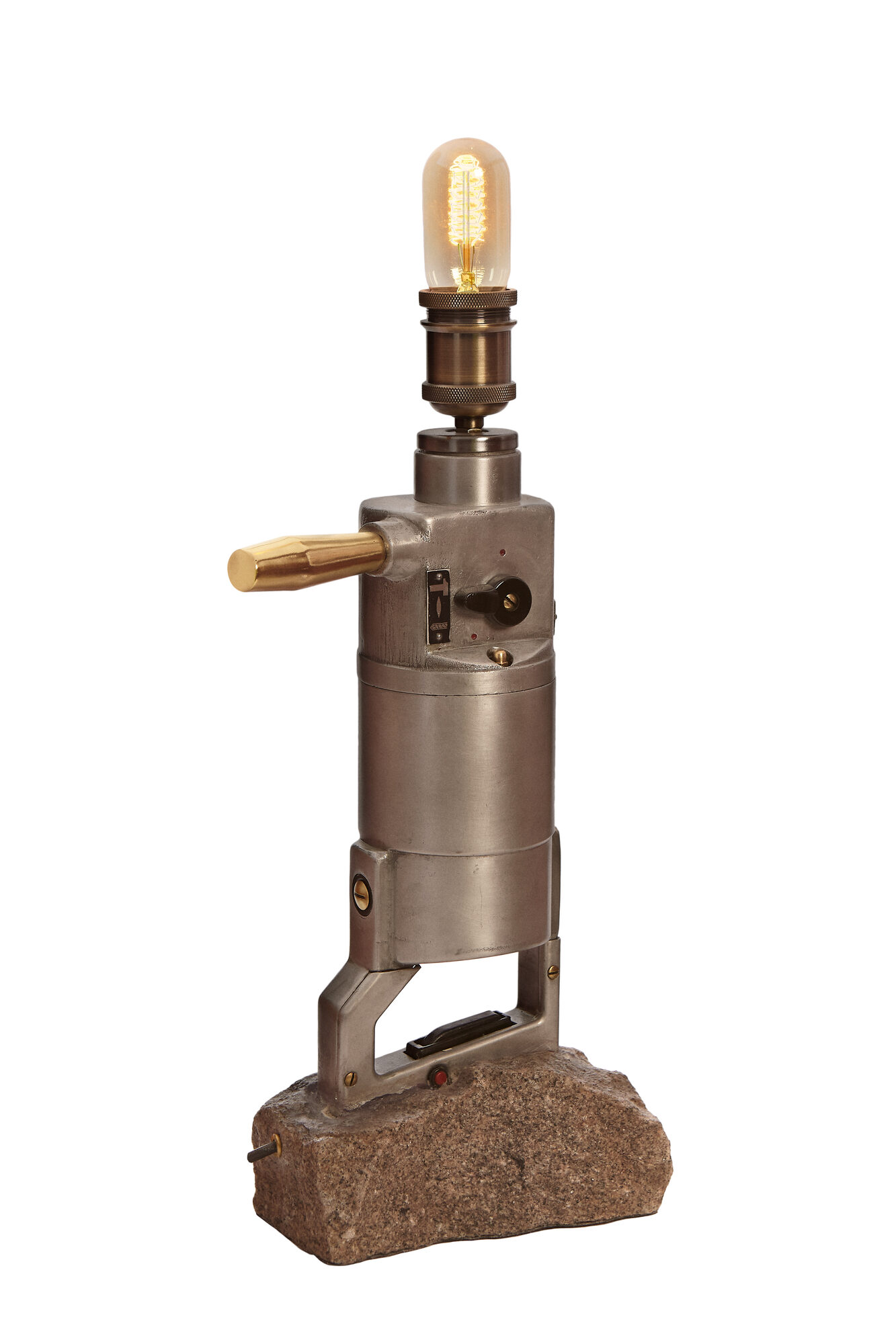 The DDR SDS Drill Lamp: a grey East German hammer drill standing upright on a rough block of Berlin granite, a brass handle on its side and an Edison bulb on top