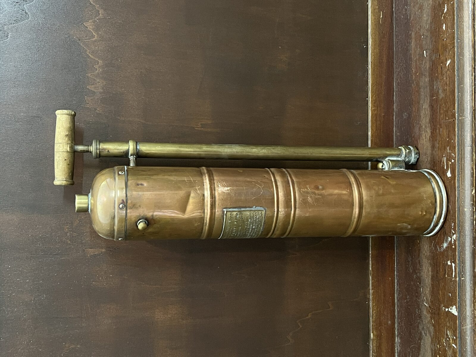 French Pump Standing Lamp before: Large copper French pump sprayer with wooden handle on a dark wooden floor