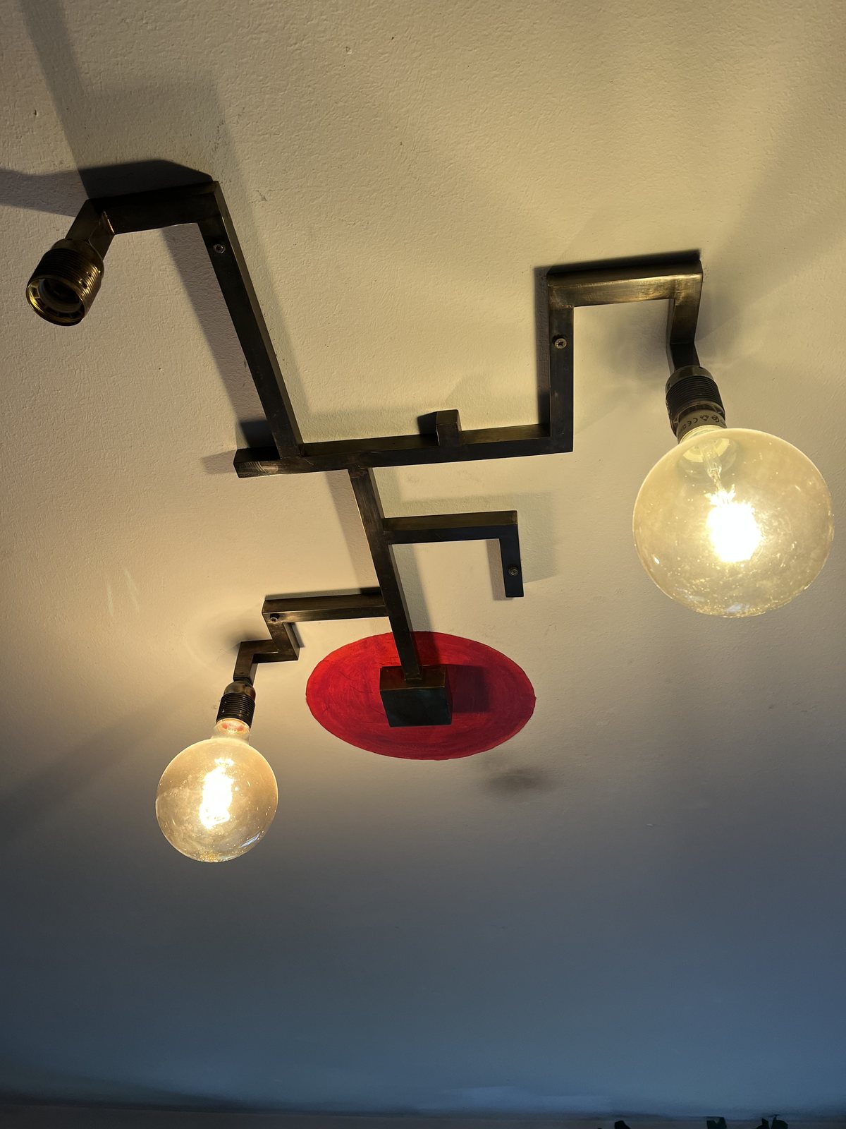 The second light from the same brass, with a red disc and large glass bulbs, on a living-room ceiling