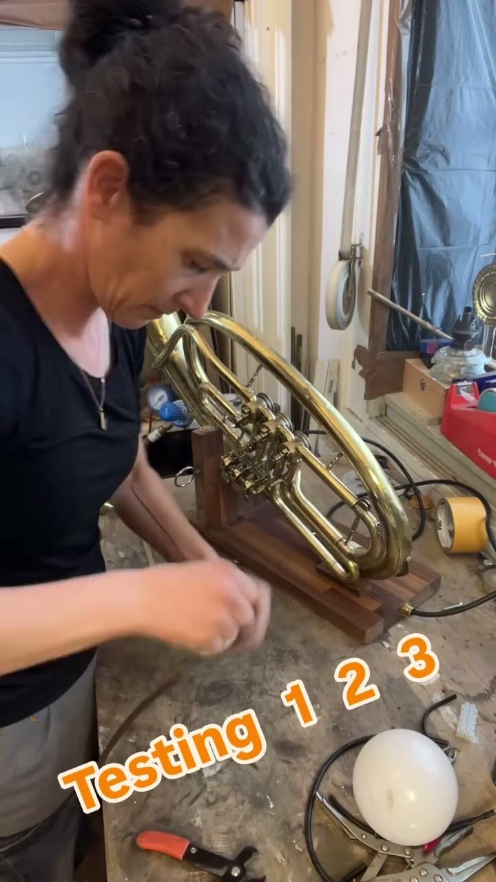 Keren concentrating at the base of the tuba, now upright on a walnut stand