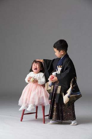 着物を着た男の子が泣いている女の子をあやしている写真