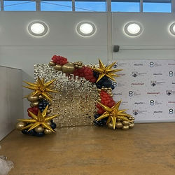 gold sequin wall with balloon garland and starburst balloons