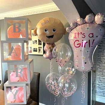 Helium-filled foil balloons for baby showers, including baby shapes, feet, and themed messages in pink and neutral tones.