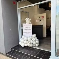 Personalised business welcome sign on easel with black and gold balloon decoration for a grand opening event.