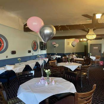 Bunches of helium-filled latex balloons in pink and silver, styled at table height for a baby shower celebration.