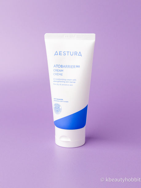 White Aestura Atobarrier 365 cream tube with blue accent on a lavender background, a clean skincare product shot.