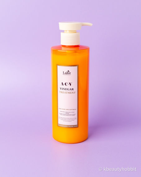 Orange pump bottle of La'dor ACV Vinegar Treatment on a lavender background, labeled for shine and softness.